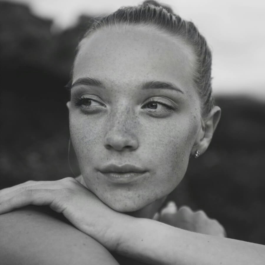 Black and white portrait of a woman with freckles and a blurred background